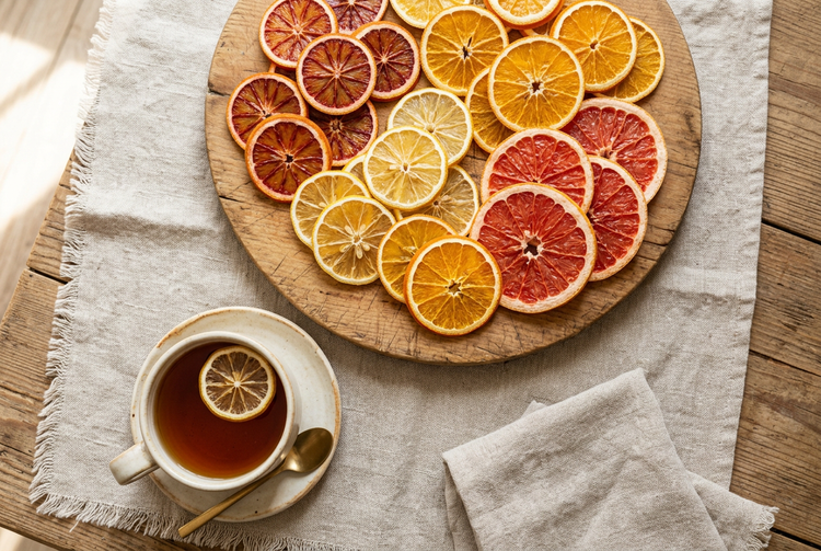 Dried citrus wheels on a cheese board beside a cup of tea